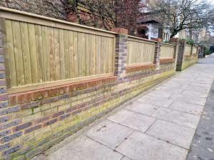 Image of Bespoke Fencing in Wimbledon SW19 with multiple customised panel sections built on top of brick wall between brick piers
